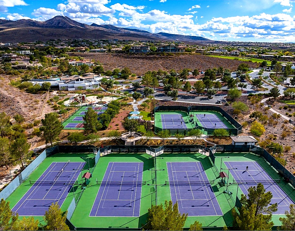 Aerial view of the purple and green courts at Anthem Country Club, community homes and desert mountains around