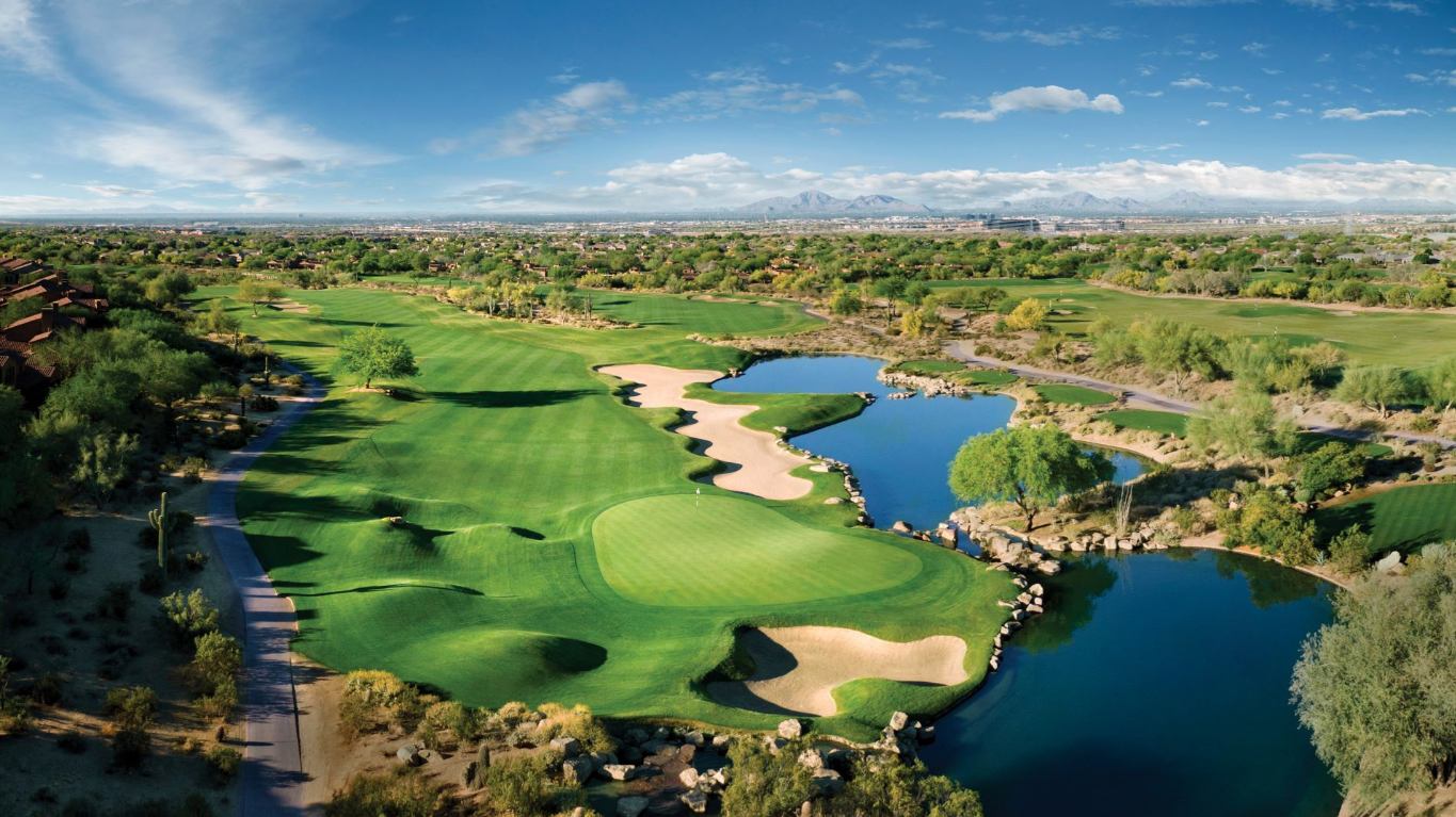 Aerial view of a Grayhawk golf course lake hole with the McDowell Mountains beyond