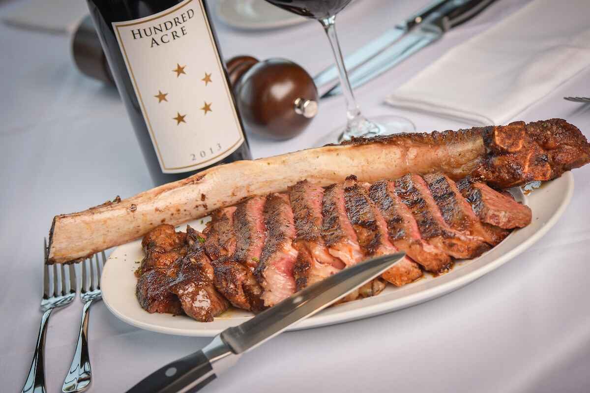 Sliced tomahawk ribeye at Steak 44 with a bottle of Hundred Acre